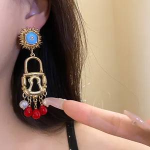 Detailed close-up of vintage sun lock earrings with dangling red beads and pearls