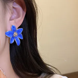 Vue détaillée de clous d'oreilles fleurs en émail bleu vintage portés par le mannequin
