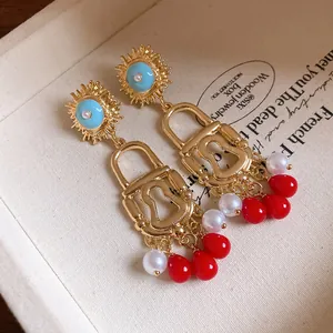 Detail view of vintage enamel sun and lock dangle earrings with red beads and pearls