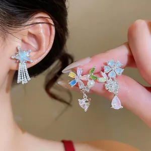 Macro detail of colorful floral and heart zircon earrings with elegant pearl accents.