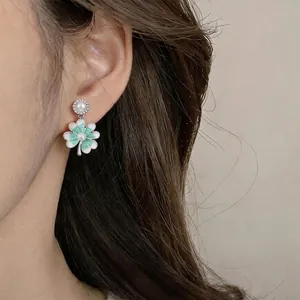 Eleganti orecchini a fiore in argento e perle con smalto verde menta indossati