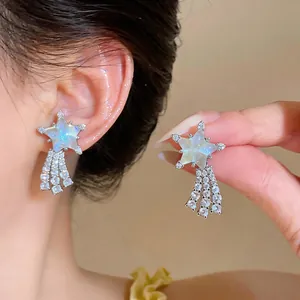 Elegant close-up of sparkling star-shaped earrings with iridescent centers and zircon tassels.