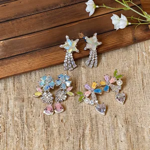 Detail of colorful zircon earrings with flower, heart and star shapes and pearl accents.