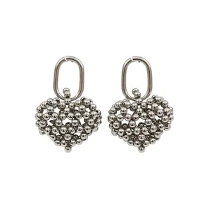 Silver hollow heart earrings with beaded design on a white background