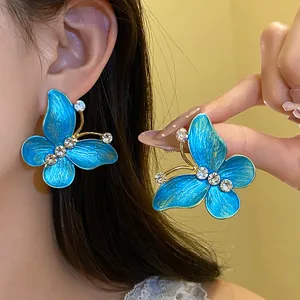 Detailed view of blue gradient butterfly stud earrings with zircons on model's ear