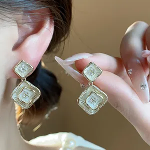 Nahaufnahme von 18K vergoldeten Emaille-Ohrringen mit funkelnden Zirkonia-Steinen.