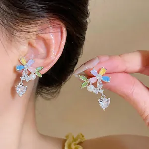 Close-up view of colorful flower stud earrings featuring heart zircon and pearl details