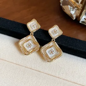 Detailansicht der 18K vergoldeten Rauten-Ohrringe mit weißem Emaille- und Zirkon-Inlay