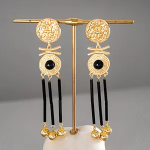 Detailed view of vintage gold-tone portrait earrings with black tassels and Greek key