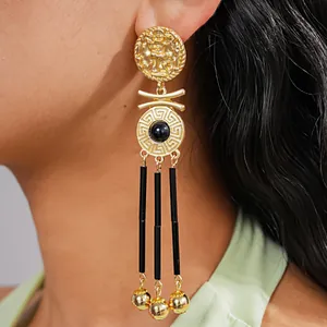 Close-up detail of vintage gold portrait earrings with black tassels and Greek key pattern