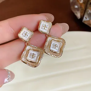 Detailansicht der 18K vergoldeten Rautenohrringe mit Zirkonia und weißer Emaille.