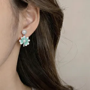 Dettaglio ravvicinato di un elegante orecchino a fiore in smalto e perla sull'orecchio
