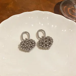 Detailed view of silver-tone hollow heart earrings with a unique beaded texture and oval hoops