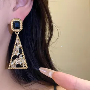 Close-up of vintage gold triangle drop earrings featuring black and clear crystals