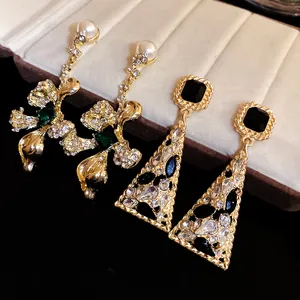 Macro view of vintage geometric triangle and floral gold-tone drop earrings with crystals