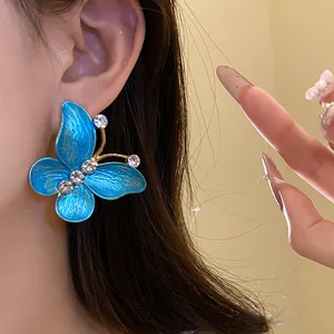 Close-up of a blue enamel butterfly earring with sparkling zircon accents on ear