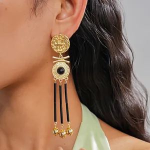 Close-up of elegant vintage gold earrings featuring Greek key pattern and black tassels