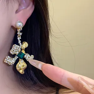 Detailed view of vintage gold drop earrings with emerald green gem and pearls