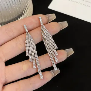 Detail of elegant silver tassel earrings with sparkling zircons held by hand