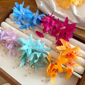 Detail view of colorful fabric flower earrings with elegant pearl tassels