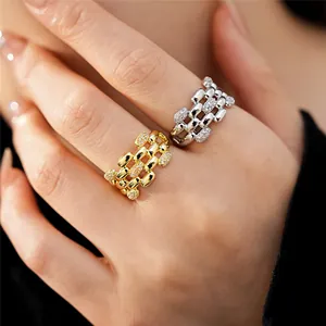 Dettaglio elegante di anelli multistrato in oro e argento con zirconi sulle dita
