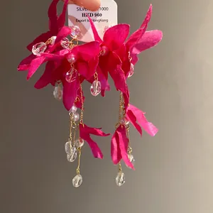 Detailed view of handmade fuchsia fabric flower earrings with pearls and crystal tassels.