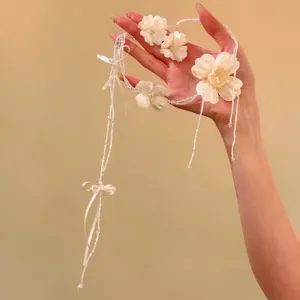 Elegante set di gioielli da sposa con fiori bianchi tenuto in mano su sfondo caldo