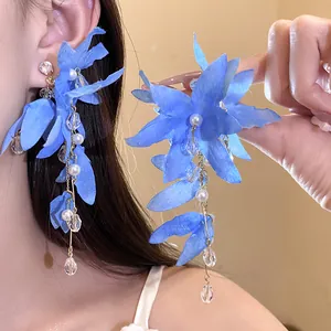 Macro view of vacation style blue fabric flower earrings with pearl and crystal tassels