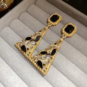 Close-up of vintage gold-tone triangle drop earrings with black and clear crystals.