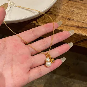 Gros plan sur l'élégant collier à double pendentif gourde avec perles et or