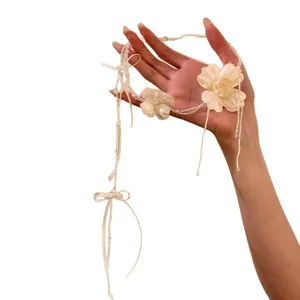 Elegante collana di fiori in tessuto bianco con nastri, ideale per sposa o feste.