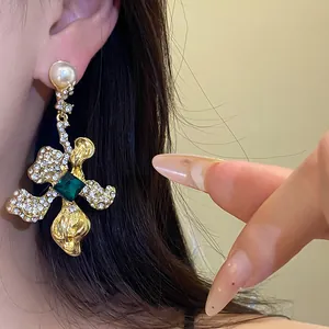 Close-up view of vintage style gold-toned drop earring with green crystal on model