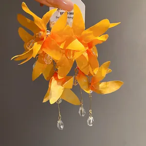 Detail view of vibrant orange fabric flower earrings with zircon and pearl tassels