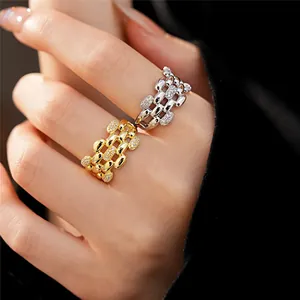 Primo piano di anelli aperti ovali traforati in zircone oro e argento indossati sulla mano.