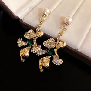 Detail shot of vintage gold dangling earrings with green gemstones and pearls