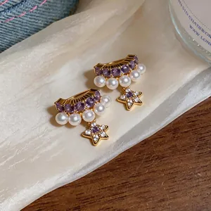 Detail shot of elegant star and pearl clip-on earrings with purple gemstones on silk.