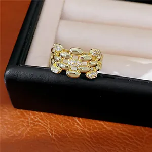 Dettaglio ravvicinato di un anello ovale cavo multistrato dorato con accenti di zircone