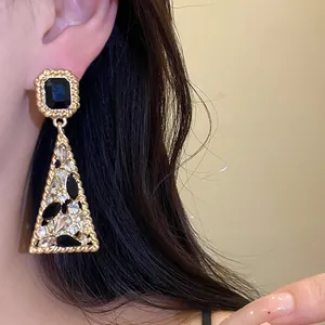 Close-up of vintage gold triangle drop earrings with black and white rhinestones