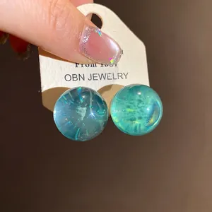 Minimalist round resin stud earrings with blue translucent cosmic planet pattern