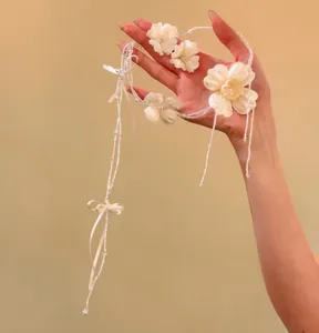 Dettaglio di un set di collana floreale bianca eterea con nastri e perle eleganti.