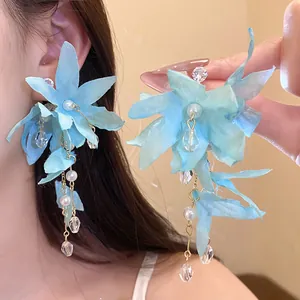 Detail of light blue fabric flower earrings with pearls and zircon tassels on model