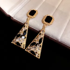 Close-up of vintage-style gold triangle dangle earrings with black and clear rhinestones.