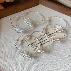 Detail view of dainty zircon enamel bow-knot hoop earrings in blue pink and white