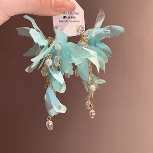 Close-up of light blue fabric flower earrings with pearls and crystals tassel details