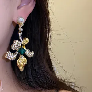 Detail view of ornate vintage drop earrings with emerald green gemstone and pearls