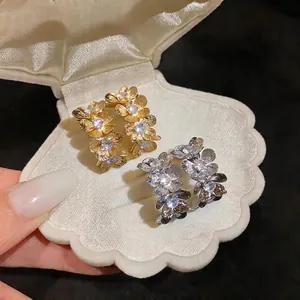 Elegantes pendientes de flor de metal con circonitas en un joyero con forma de concha