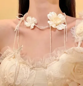 Primo piano di un elegante girocollo floreale bianco con nastri su abito da sposa in pizzo