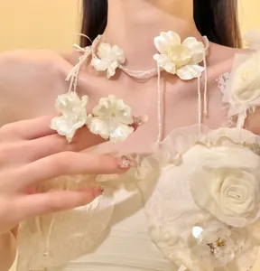 Primo piano che mostra i delicati fiori di seta bianca e le catene di perle del choker