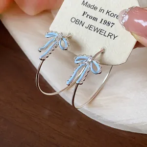 Close-up of light blue enamel bowknot hoop earrings with sparkling zircon detail