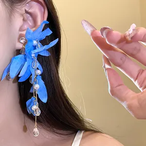 Close-up of blue fabric flower tassel earring with pearls on a woman's ear
